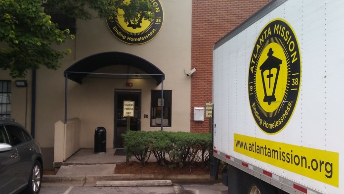 Exterior entrance showing covered visitor area with black awning, signage, and brick architectural details