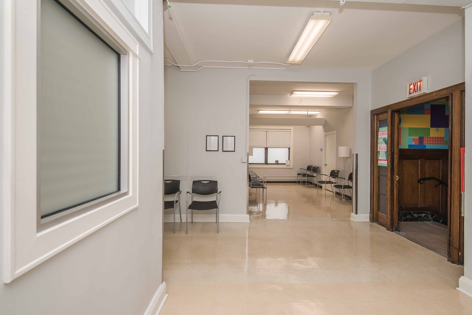 Interior multipurpose room with seating area, whiteboard, colorful wall art, exits, and open floor plan for group activities