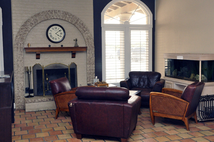 Interior living space with burgundy leather seating, fireplace with stone arch, wooden furniture, and decorative accents
