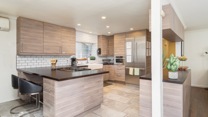Interior kitchen featuring light wood cabinetry, white subway tile backsplash, center island with seating, stainless steel appliances
