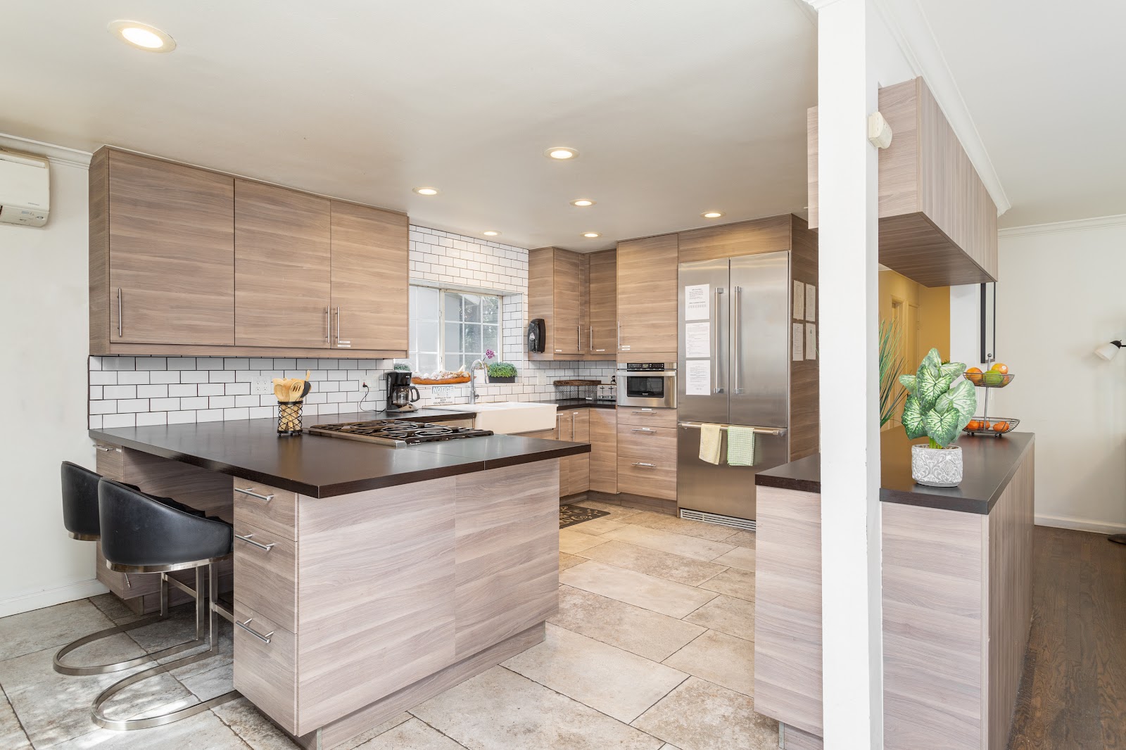 Interior kitchen featuring light wood cabinetry, white subway tile backsplash, center island with seating, stainless steel appliances