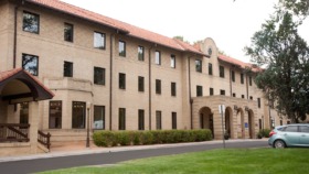 Exterior front view of multi-story brick building with arched windows, entry portico, and landscaped grounds