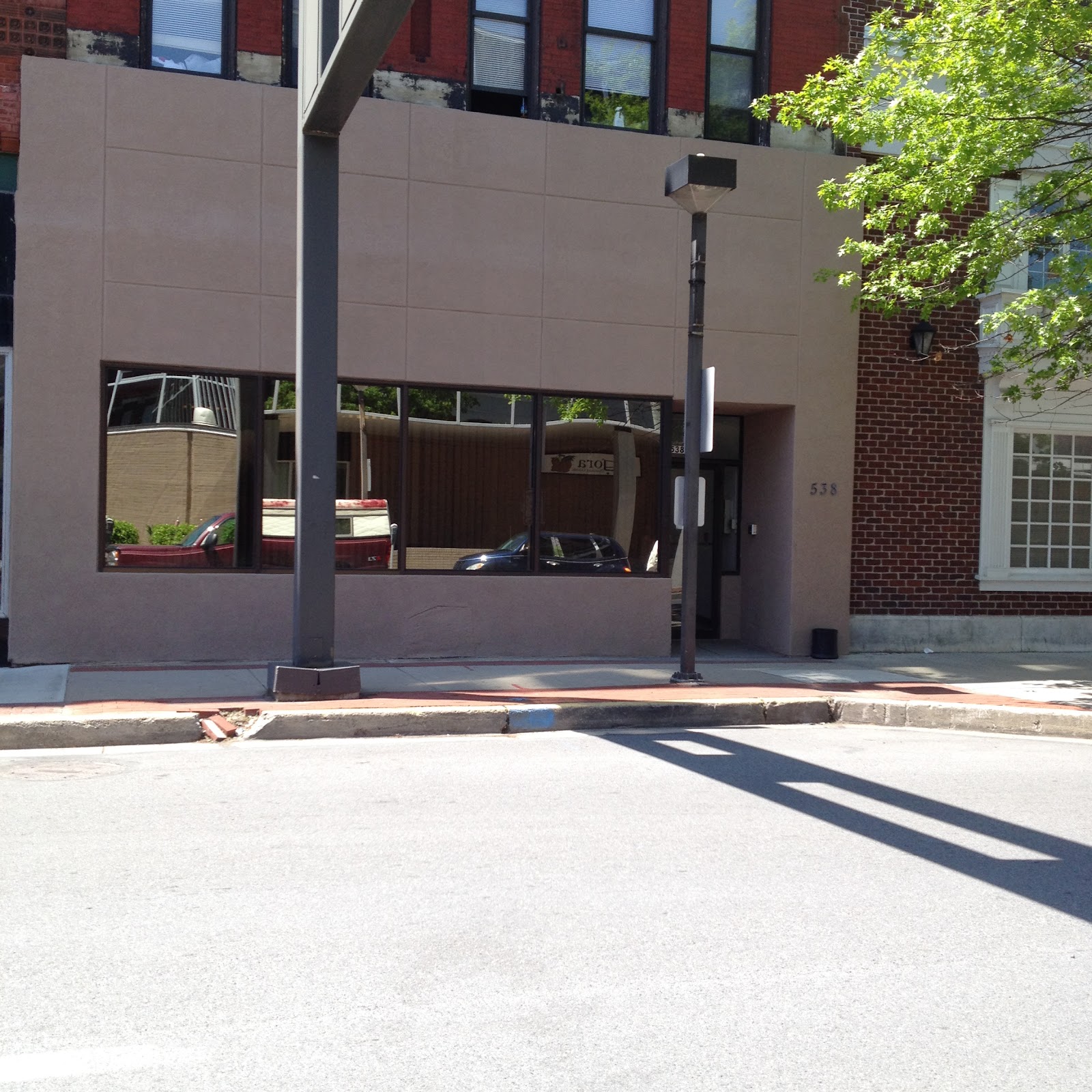 Exterior view of treatment facility entrance with modern facade, dark windows, and brick building adjacent