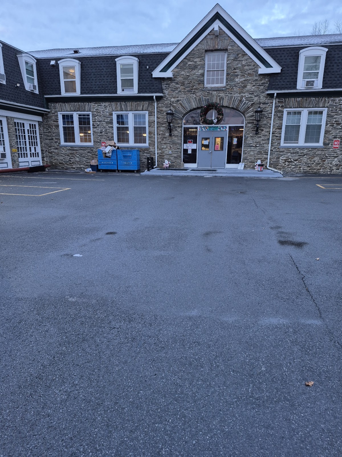 Exterior view of stone and shingle residential treatment facility with main entrance, multiple windows, and parking area