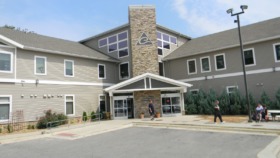 Exterior view of Eisenhower Center showing main entrance with stone chimney, glass doors, and manicured landscaping