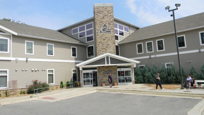 Exterior view of Eisenhower Center showing main entrance with stone chimney, glass doors, and manicured landscaping