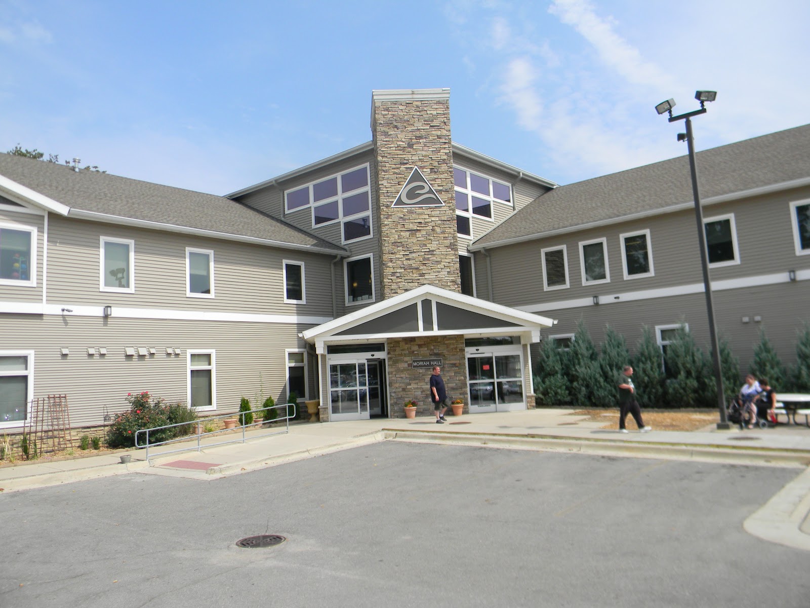 Exterior view of Eisenhower Center showing main entrance with stone chimney, glass doors, and manicured landscaping