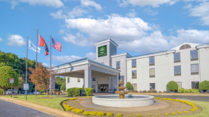 Exterior view of treatment facility main entrance with white building, green landscaping, fountain, and flags