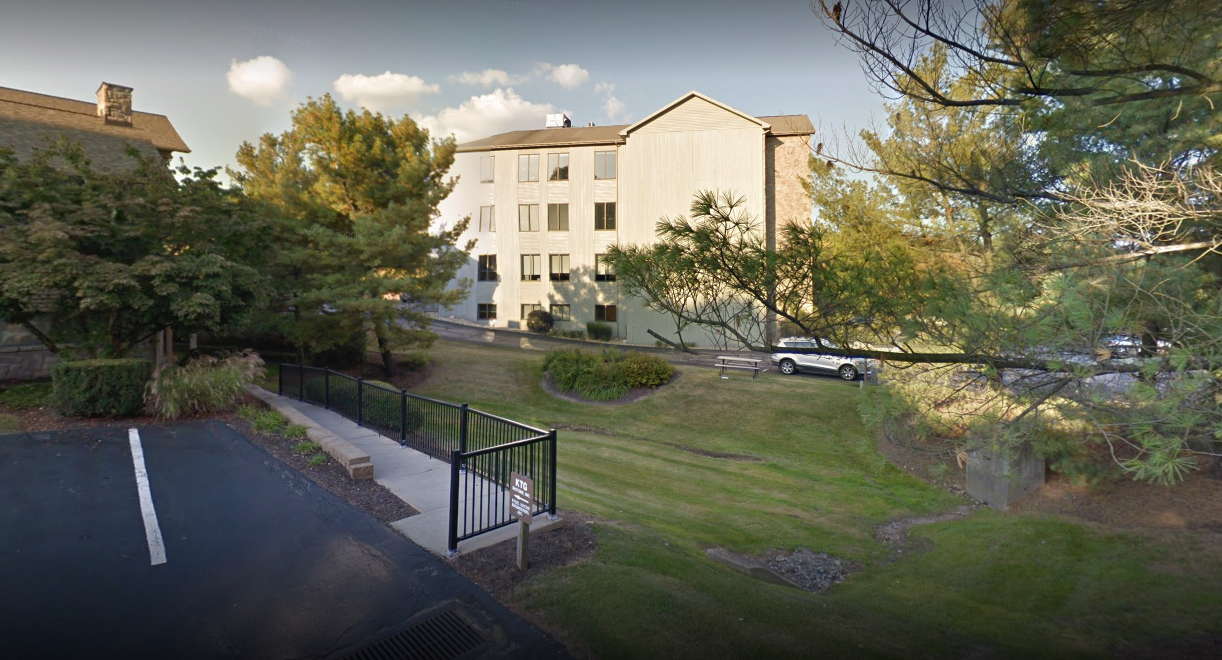 Exterior view of multi-story treatment facility with parking area, landscaped grounds, and main building entrance