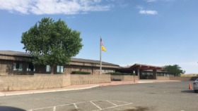 Exterior view of Crownpoint Healthcare Facility with brick facade, entrance, flagpole, and visitor parking area