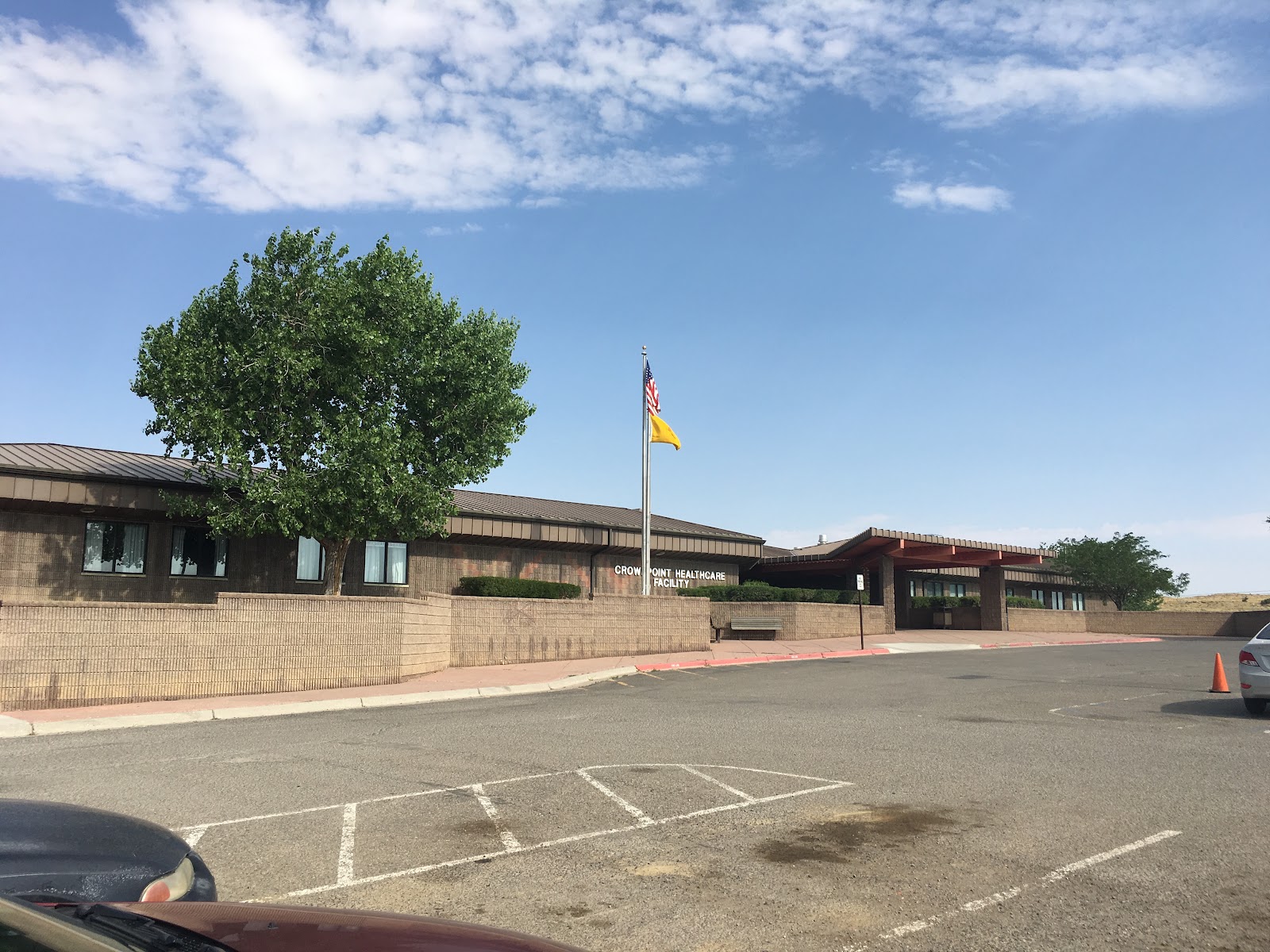 Exterior view of Crownpoint Healthcare Facility with brick facade, entrance, flagpole, and visitor parking area