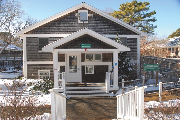 Exterior front entrance showing white covered porch with accessible ramp, glass doors, and shingled building facade