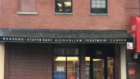 Exterior front entrance of Bedford-Stuyvesant Alcoholism Treatment Center showing black awning with white lettering and glass doors at 722 Myrtle Avenue
