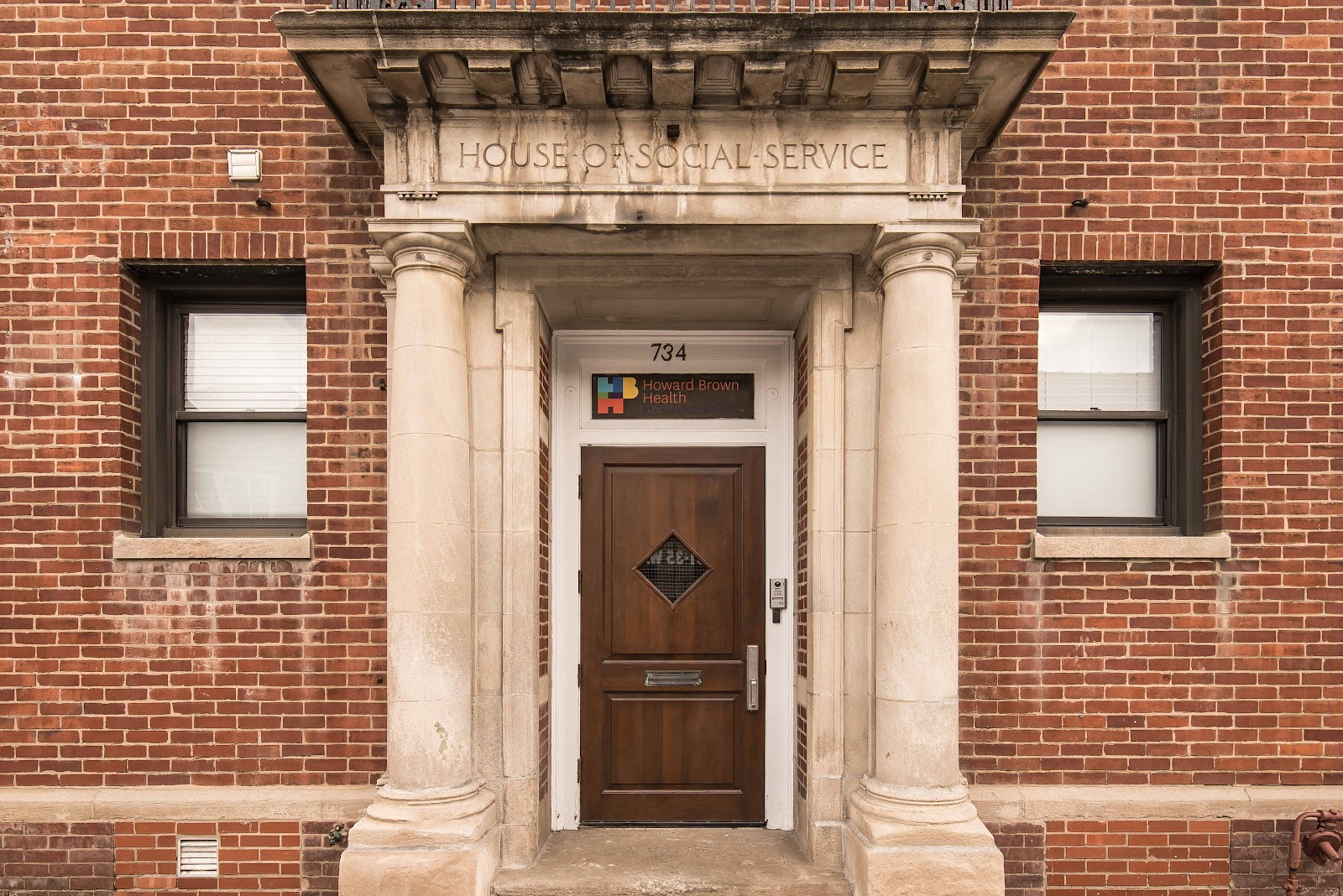 Exterior front entrance of brick building showing address 734, main door with ornamental columns, and Thresholds facility signage
