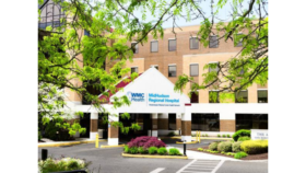 Exterior front entrance of MidHudson Regional Hospital showing brick building, white canopy with logo, manicured landscaping, and parking area