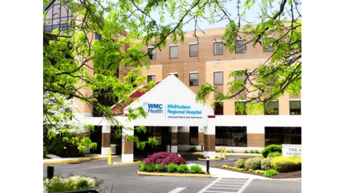 Exterior front entrance of MidHudson Regional Hospital showing brick building, white canopy with logo, manicured landscaping, and parking area