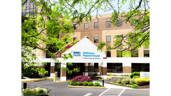 Exterior front entrance of MidHudson Regional Hospital showing brick building, white canopy with logo, manicured landscaping, and parking area