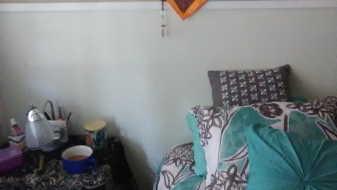 Interior bedroom with bed, nightstand, decorative wall art, knitted blanket, personal belongings, and window natural light