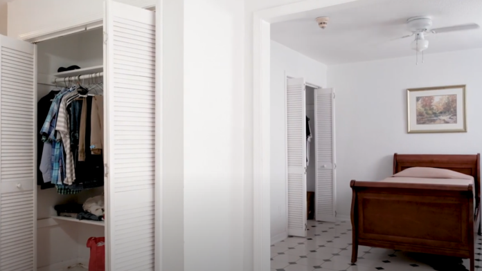 Interior bedroom featuring wooden bed frame, closet with clothing storage, artwork, and tile flooring