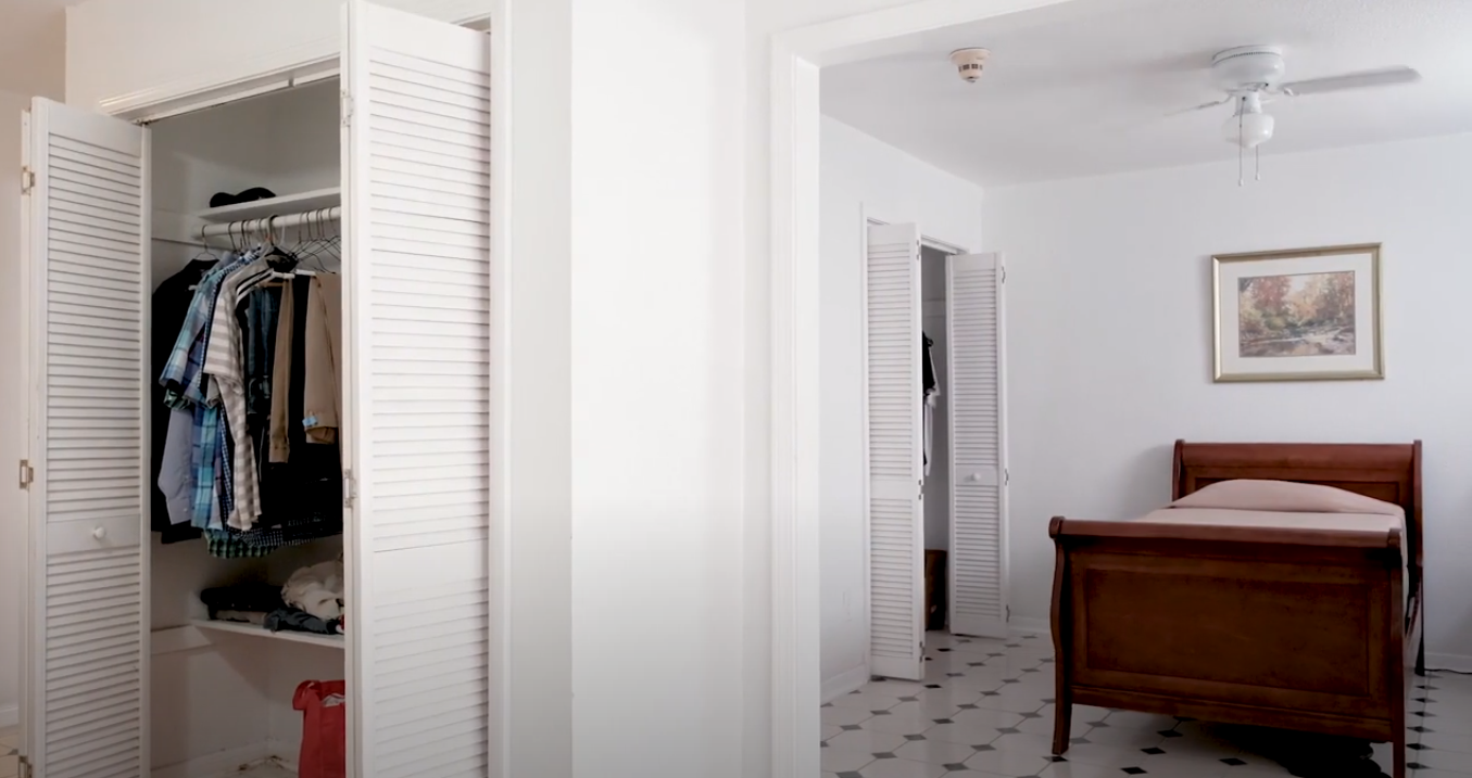 Interior bedroom featuring wooden bed frame, closet with clothing storage, artwork, and tile flooring
