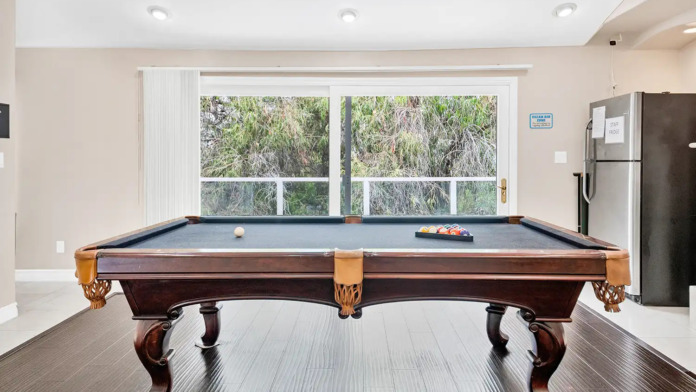 Interior recreation room featuring pool table, fireplace, flat-screen TV, and large windows with natural light