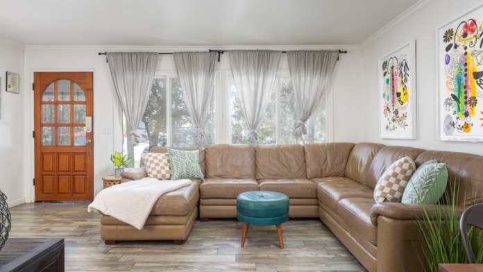 Interior common area featuring large tan leather sectional sofa, wooden coffee table, arc lamp, artwork, and glass patio doors
