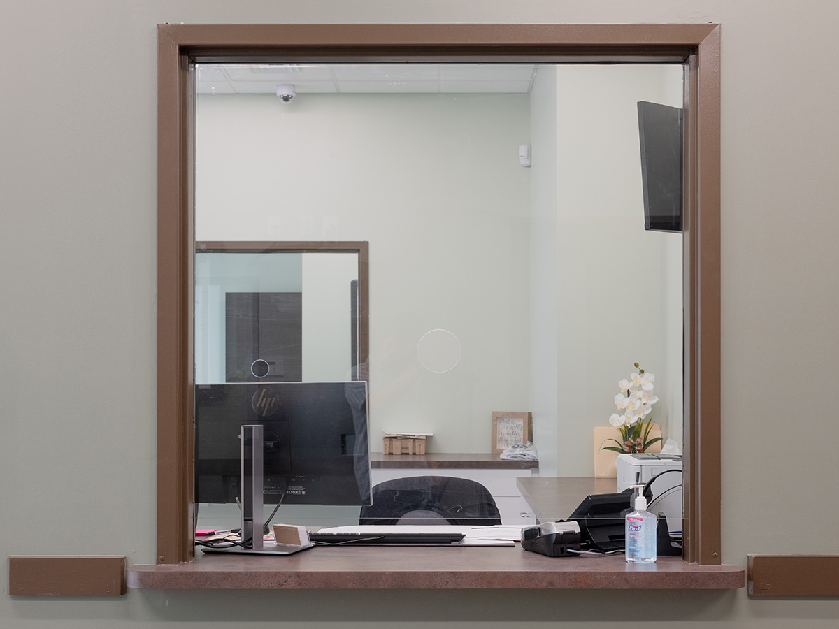 Interior office window with desktop computer setup, monitor, desk supplies, and plant decoration
