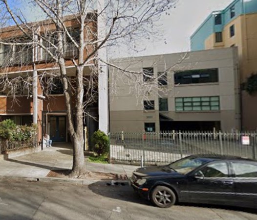 Exterior view of treatment facility showing front facade with multi-story building, street parking, and white picket fence
