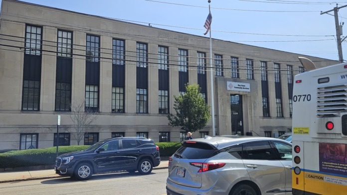 Exterior of treatment facility showing front facade, street parking, and transit bus visible in background