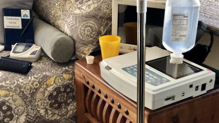 Interior treatment space with patient bed, medical IV stand, monitoring equipment, and supportive furnishings