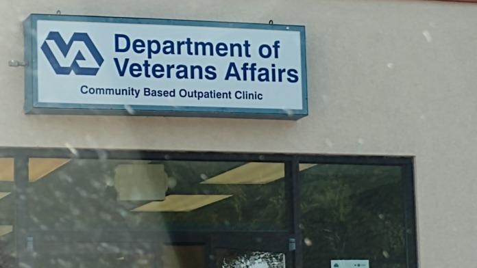 Exterior signage showing Department of Veterans Affairs Community Based Outpatient Clinic logo and name on building entrance with glass doors