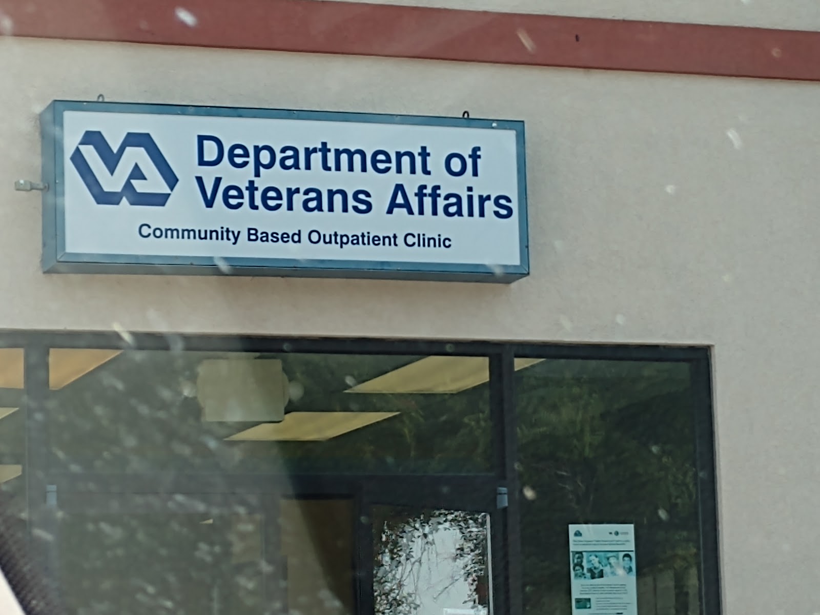 Exterior signage showing Department of Veterans Affairs Community Based Outpatient Clinic logo and name on building entrance with glass doors