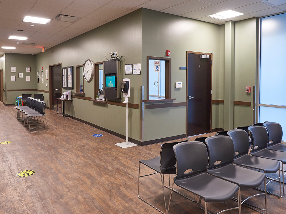 Interior waiting area showing black chairs, clock, treatment windows, and doors along hallway