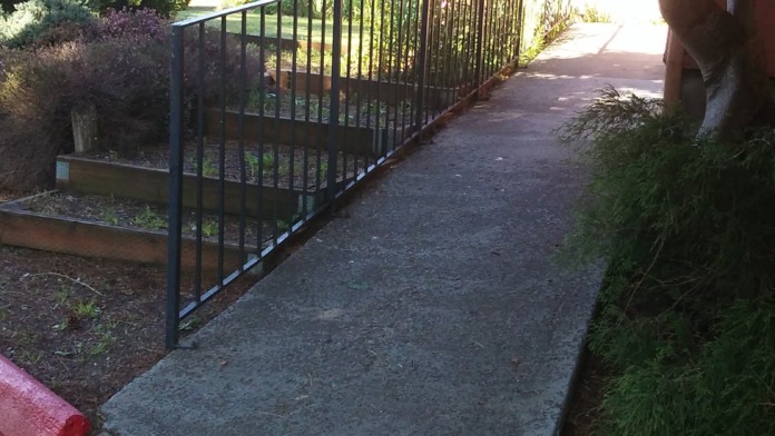 Exterior showing accessible pathway with black metal railing leading to facility entrance with building structure