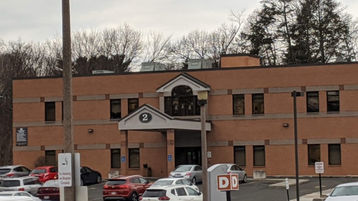 Exterior of brick administrative building with entrance doors and parking area, marked with building number 2
