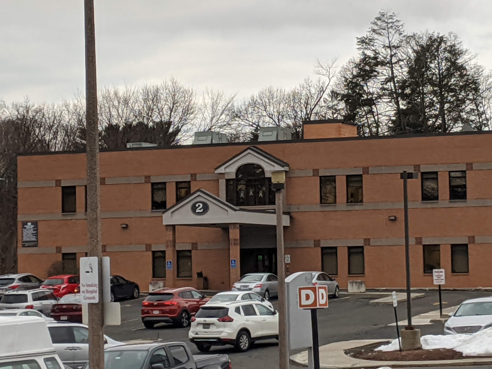 Exterior of brick administrative building with entrance doors and parking area, marked with building number 2