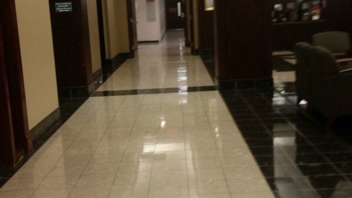 Interior hallway with administration signage, dark wood paneling, tiled flooring, and professional workplace setting