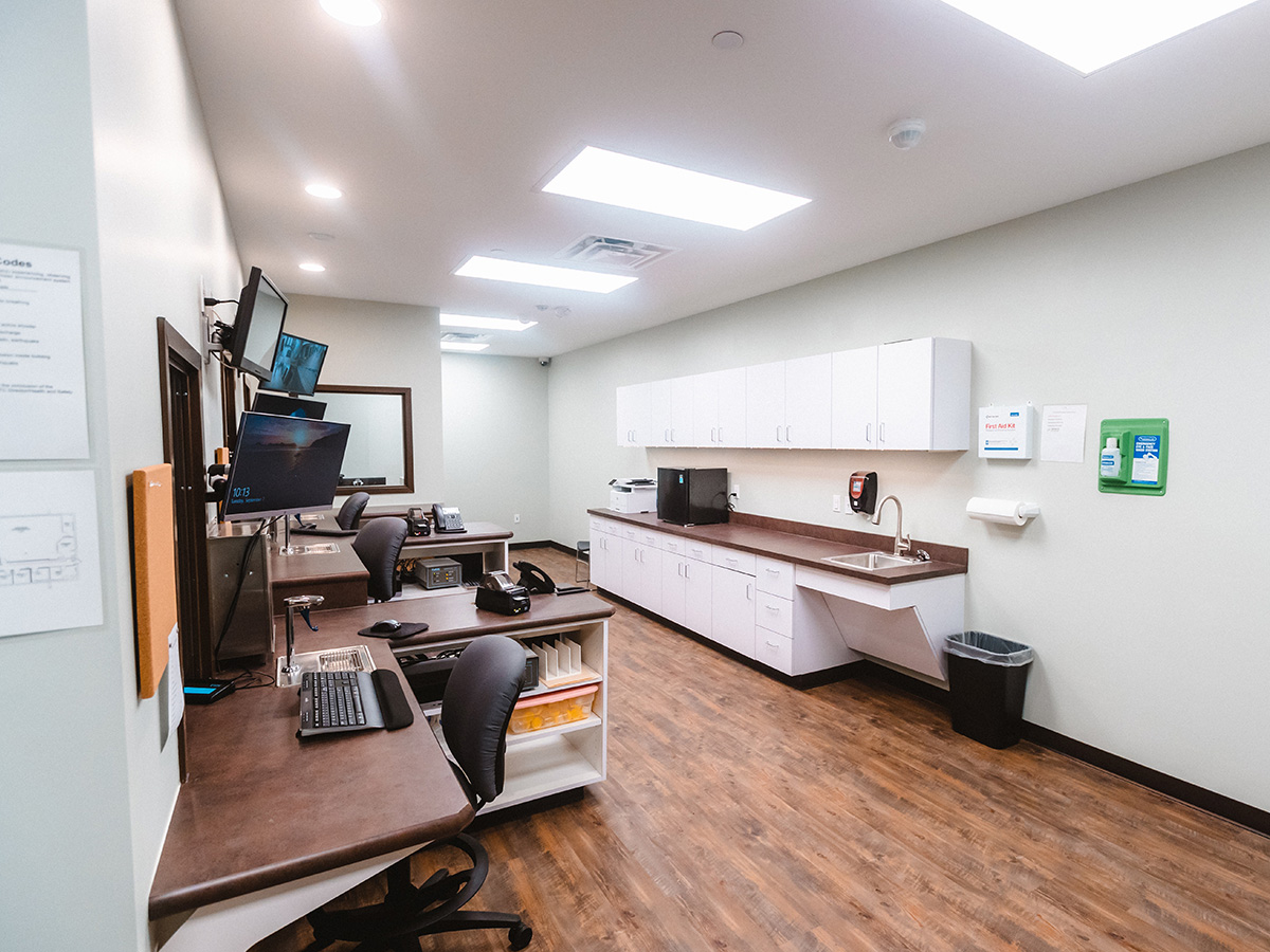 Interior office space with desktop computer, white cabinetry, sink, and professional workplace furnishings