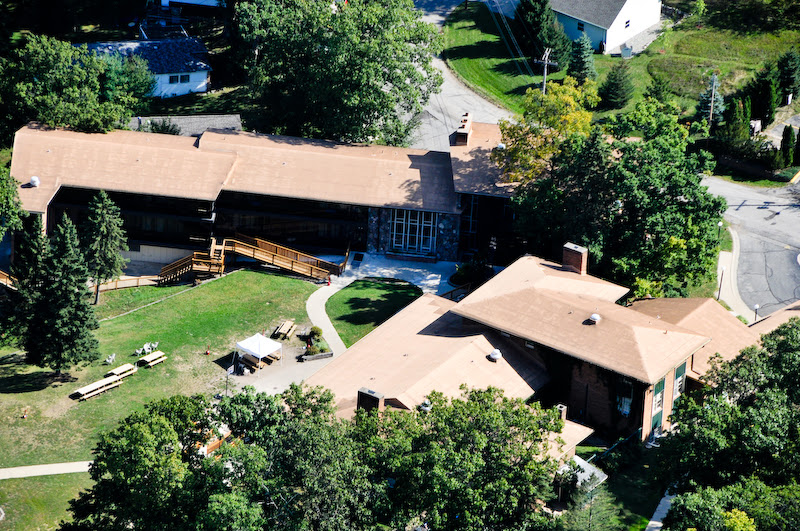 Overhead view of facility campus showing connected buildings, grounds, landscaping, and surrounding vegetation