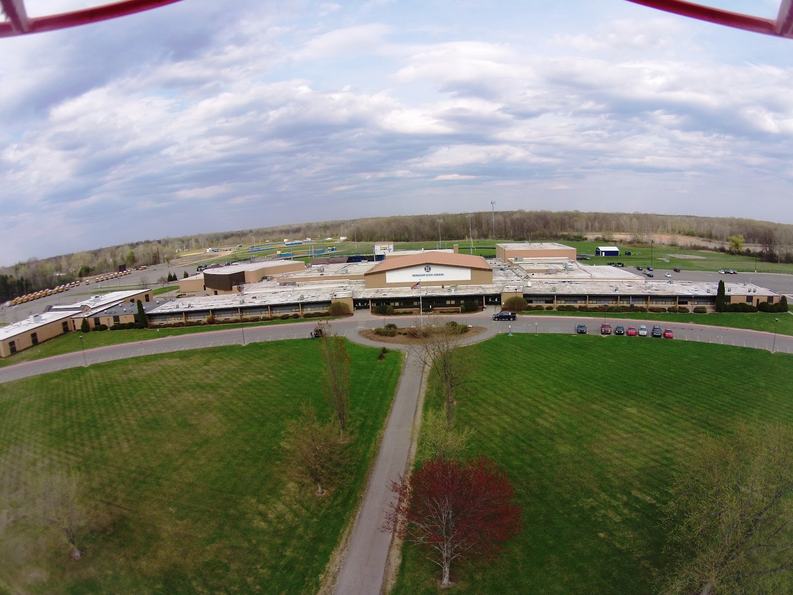 Aerial view of entire school campus showing brick building complex, parking areas, athletic fields, and surrounding grounds