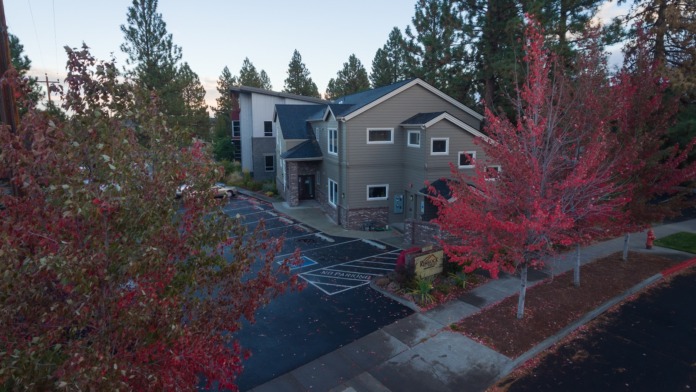 Exterior aerial view of two-story gray treatment facility building surrounded by landscaping and autumn foliage trees.