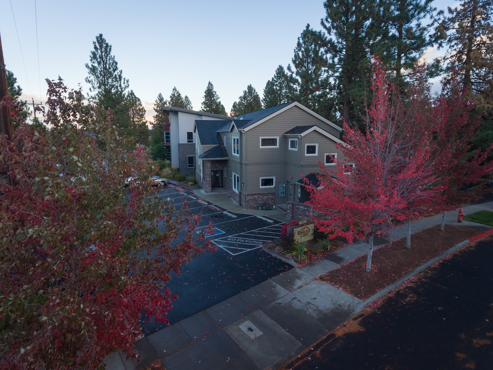 Exterior aerial view of two-story gray treatment facility building surrounded by landscaping and autumn foliage trees.