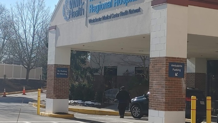 Exterior ambulatory care entrance building showing signage, brick facade, parking area with yellow bollards, and landscaping