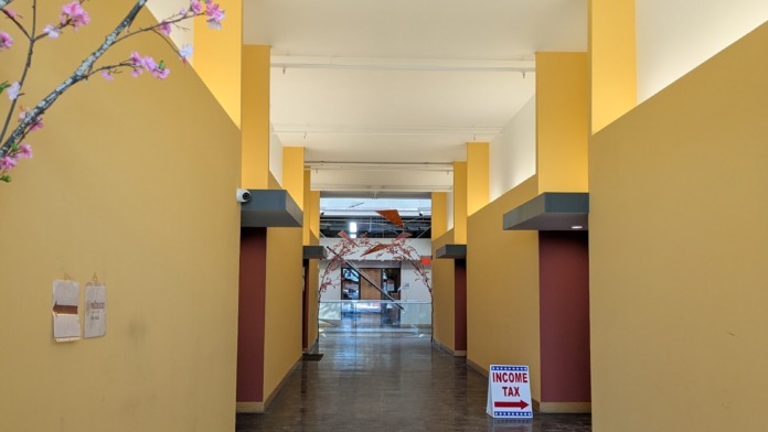 Interior hallway with yellow and burgundy architectural columns, purple flowering branch decoration, and polished flooring