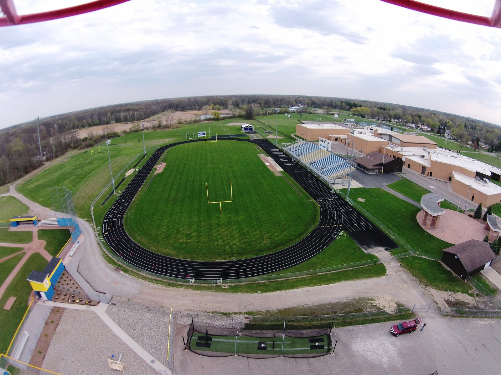 Aerial view of outdoor athletic facilities including football field with track, soccer fields, and sports equipment on school campus