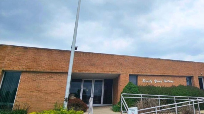 Exterior of brick building with main entrance, landscaping, ramp access, and signage