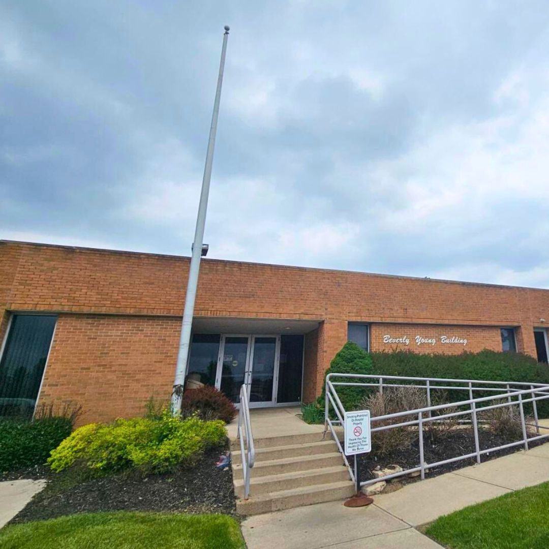 Exterior of brick building with main entrance, landscaping, ramp access, and signage