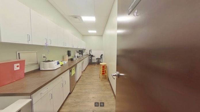 Interior staff break room with long countertop, white cabinetry, refrigerator, microwave, and sink facilities