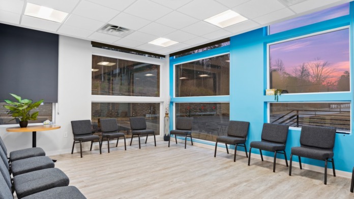Interior common area with bright blue accent walls, large windows, gray seating chairs, and natural light from windows