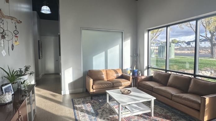Interior lounge with brown leather sofas, white table, black ceiling with skylights, and large windows with outdoor views.